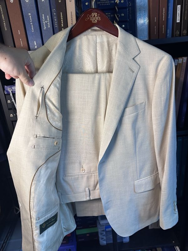 Cream summer suit held open to show a tonal paisley lining and tan piping
